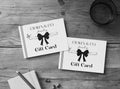 Two 'Craven & Co. Jewellery' gift cards on a wooden surface with a pen and notebook.